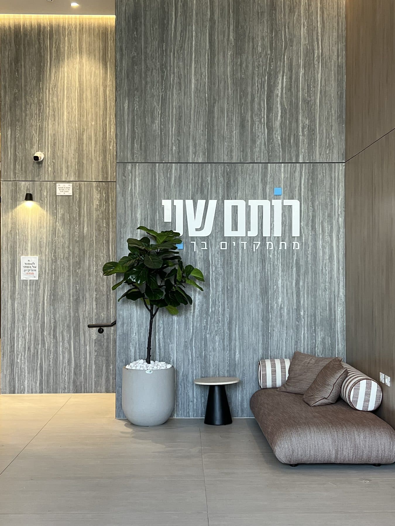 לובי בניין המגורים בנתניה, עם מצלמת כיפה על קיר האבן
